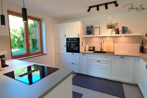 una cocina con armarios blancos y electrodomésticos negros en Homely Stay Velosoph Quartier en Bayrischzell
