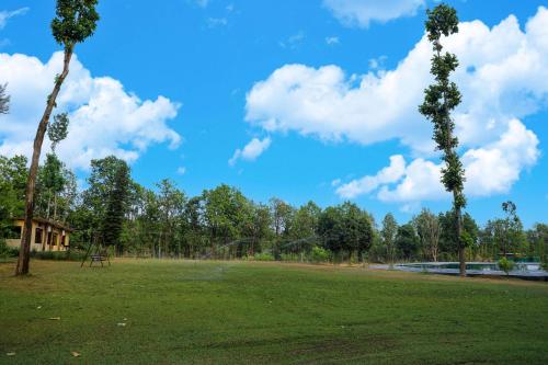 a park with two palm trees and a blue sky at Hideaway By Aahma in Rāmnagar