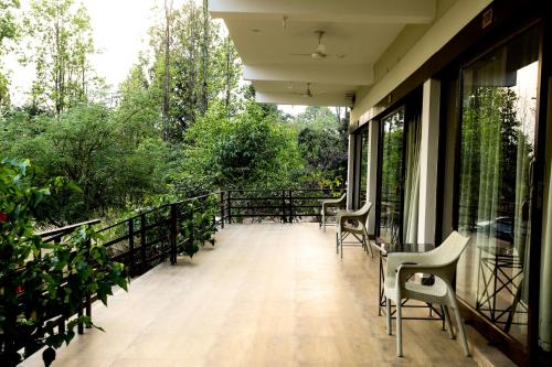 a balcony with chairs and tables and trees at Hideaway By Aahma in Rāmnagar
