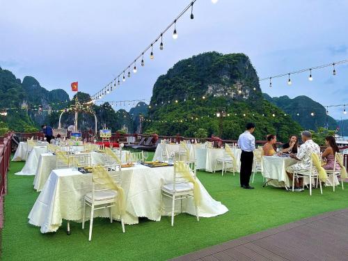 um grupo de mesas e cadeiras com pessoas sentadas em Amanda Legend Cruise Ha Long Bay em Ha Long