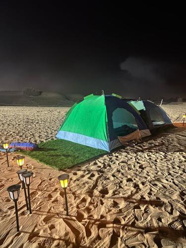 a tent and lights on a sandy beach at Dubai Tourism and Travel Services in Hunaywah
