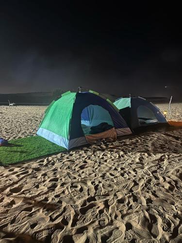 dos tiendas de campaña en una playa de arena con una tormenta acercándose en Dubai Tourism and Travel Services en Hunaywah