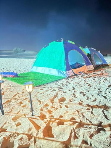 two tents on a sandy beach next to the water at Dubai Tourism and Travel Services in Hunaywah