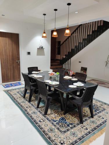 a dining room with a black table and chairs on a rug at The Marigold Villa in Pune