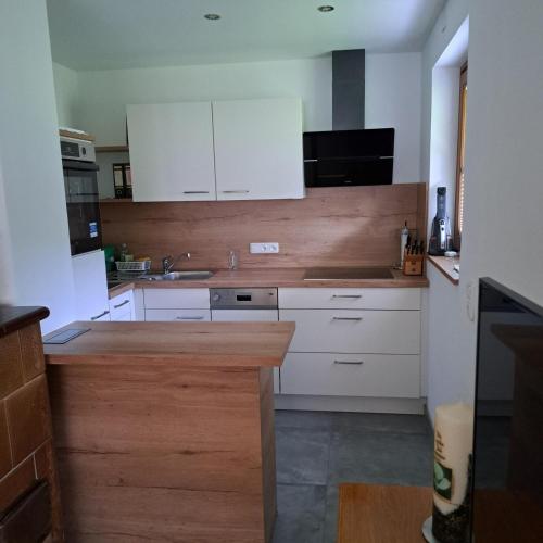 a kitchen with white cabinets and a wooden counter top at Ferienwohnung Schlemmer Romed Dolomitenblick in Nußdorf