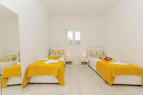 2 Betten in einem weißen Zimmer mit gelben Decken in der Unterkunft Family friendly house with 3 rooms,big pool and grill near Split in Kaštel Sućurac