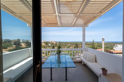 een uitzicht vanaf het balkon van een huis met een glazen tafel bij Krinos Suite-Magnificent Sea view in Chersonissos
