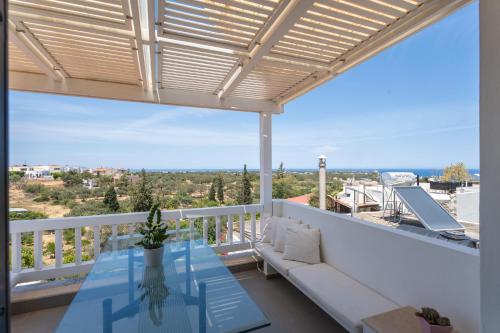 einen Balkon mit einem Sofa und einem Glastisch in der Unterkunft Krinos Suite-Magnificent Sea view in Hersonissos