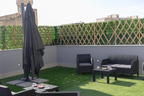 a patio with two chairs and an umbrella and tables at Elysium Affittacamere in Mazara del Vallo