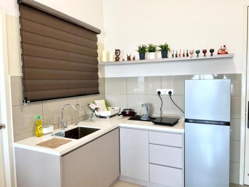 a white kitchen with a sink and a refrigerator at Amber Cove Melaka in Melaka