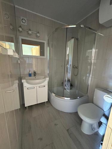 a bathroom with a shower and a toilet and a sink at Domki Milka in Ustka