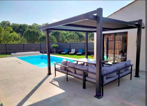 un pavillon avec un banc à côté d'une piscine dans l'établissement Maison climatisée avec piscine chauffée, à Cazilhac
