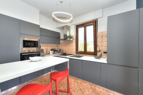 a kitchen with a white counter and a red stool at La Vela Deluxe in Salò