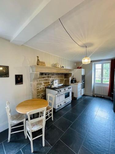 une cuisine avec une table, des chaises et une cuisinière dans l'établissement Maison de charme proche du lac, à Royère-de-Vassivière