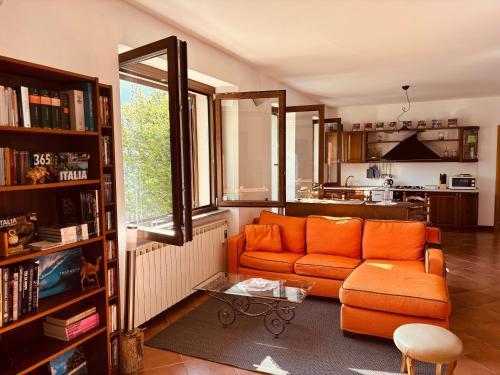 a living room with an orange couch and a kitchen at Incanto Nesso Parking and Lake View in Nesso