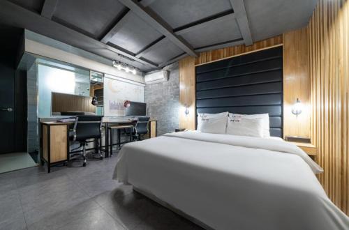 1 dormitorio con 1 cama blanca grande y escritorio en Hotel Trip en Incheon