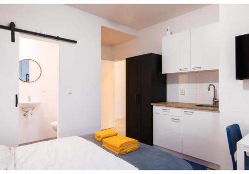 una cucina con armadi bianchi e asciugamani gialli su un letto di Tilburg City, New Rooms And A Kitchen a Tilburg