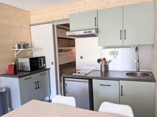une petite cuisine avec des armoires blanches et un évier dans l'établissement Studio 25m2, 5 pers, 30m des pistes, balcon sud, à Villard-de-Lans