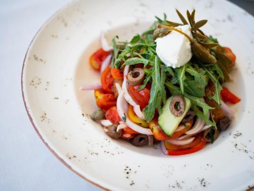 a white plate of food with a salad on it at Dracos Hotel in Parga