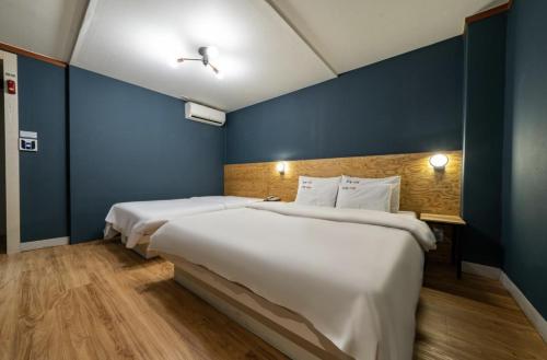 two beds in a room with blue walls and wooden floors at Hotel Trip in Incheon