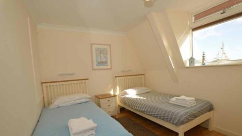 zwei Betten in einem kleinen Zimmer mit Fenster in der Unterkunft Beach View House - Self Catering Hayle, St Ives Bay Cornwall in Hayle