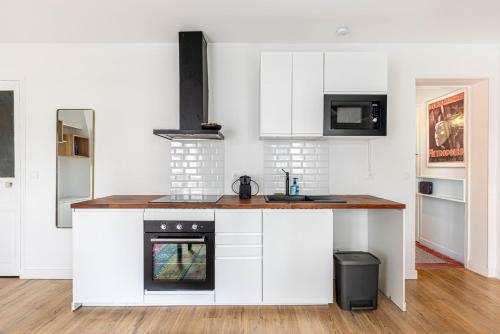 une cuisine avec des armoires blanches et un four à plaques de cuisson dans l'établissement GuestReady - Cosy Nest near Place de la Bastille, à Paris