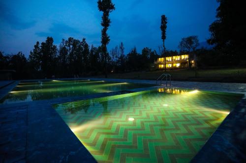 a swimming pool at night with a house in the background at Hideaway By Aahma in Rāmnagar