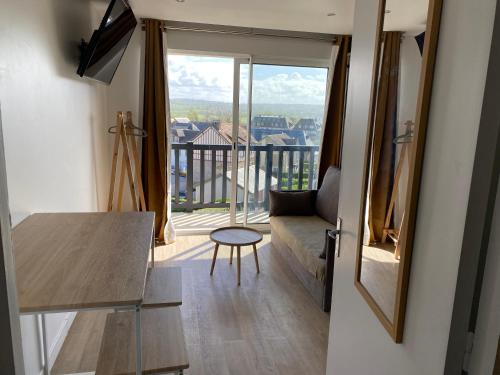 een woonkamer met een bank en een tafel bij beau studio au bord de la mer in Blonville-sur-Mer