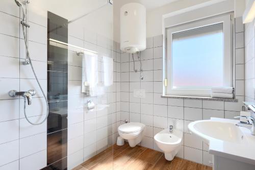 a white bathroom with a toilet and a sink at Villa Lara 1 in Ližnjan