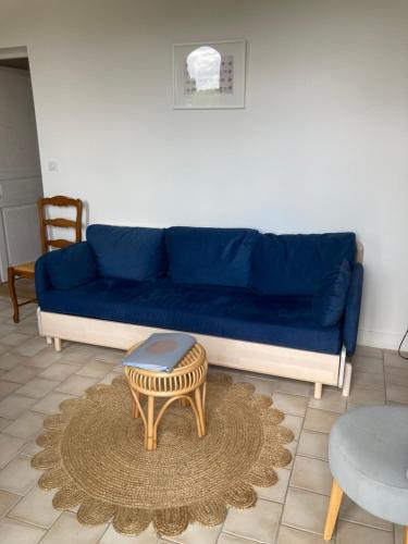 een blauwe bank met een tafel in de woonkamer bij Clos Phitarra, charmant gîte pour 2 personnes à 7 mns d'Etretat in Les Loges