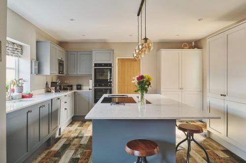 a kitchen with white cabinets and a counter with stools at Sandy Hill Farm in Curborough