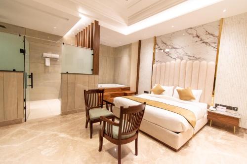 a bedroom with a bed and a table and chairs at Hotel Miracle Resort in Phagwāra