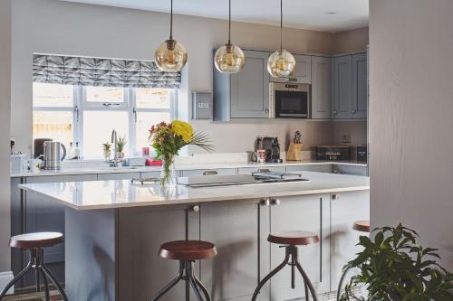 a kitchen with white cabinets and bar stools at Sandy Hill Farm in Curborough