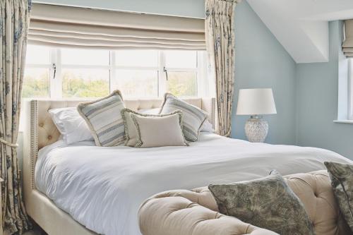 a large white bed with pillows and a window at Sandy Hill Farm in Curborough