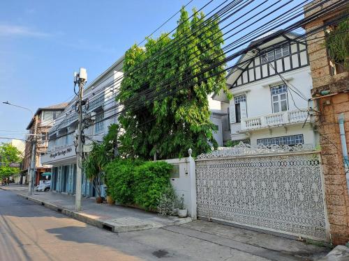 une maison blanche avec une clôture blanche et un arbre dans l'établissement Wiengket Heritage 1964, à Bangkok