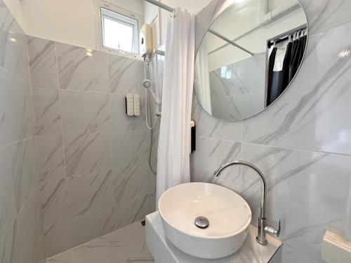 a white bathroom with a sink and a mirror at Na Ekkamai Residence in Bangkok
