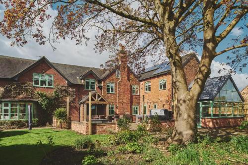 a large brick house with a tree in the yard at Sandy Hill Farm in Curborough