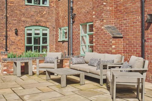 a patio with couches and tables in front of a brick building at Sandy Hill Farm in Curborough