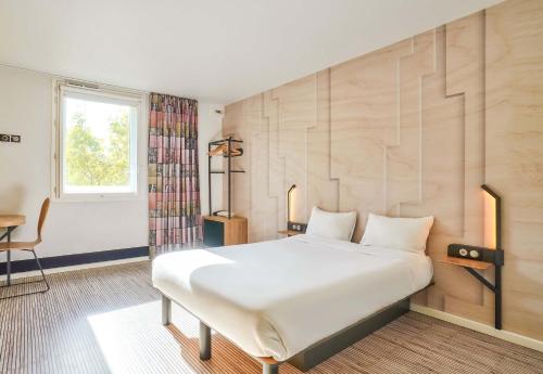 Un dormitorio con una gran cama blanca y una ventana en B&B HOTEL Paris Malakoff Parc des Expositions, en Malakoff