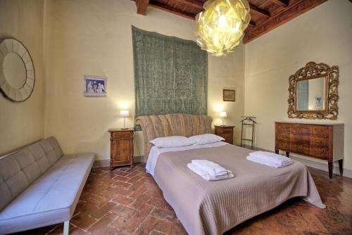 ein Schlafzimmer mit einem Bett, einem Sofa und einem Spiegel in der Unterkunft Montegufoni by PosarelliVillas in Montagnana Val di Pesa
