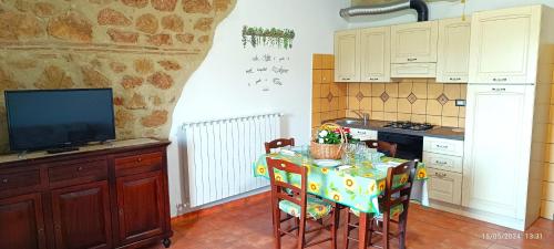 een keuken met een tafel met stoelen en een televisie bij Casavacanze Pergolino con piscina ad uso esclusivo in Acquapendente