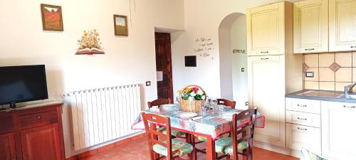 een keuken met een tafel met stoelen en een televisie bij Casavacanze Pergolino con piscina ad uso esclusivo in Acquapendente