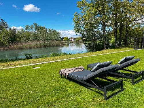 two benches sitting on the grass next to a river at Jesolo Luxury Suites in Jesolo