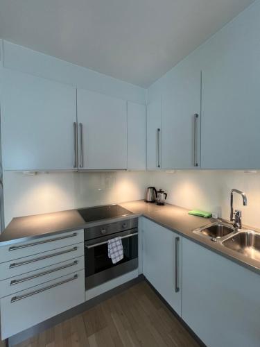 a kitchen with white cabinets and a sink at Kanalen 3 Tjuvholmen in Oslo