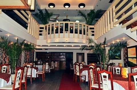ein Esszimmer mit roten Stühlen und Tischen in einem Restaurant in der Unterkunft Different Hotel & Restaurant in Divjaka