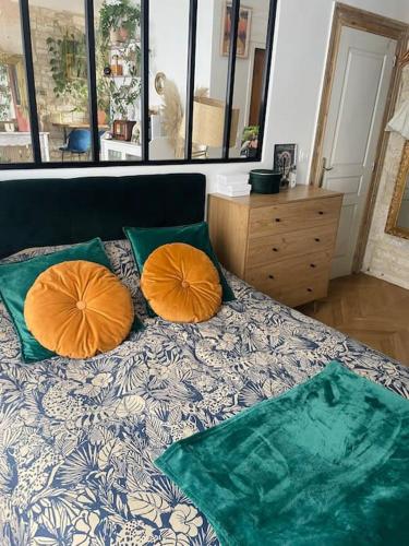 - un lit avec 2 oreillers orange dans l'établissement Appartement coup de cœur, à Caen
