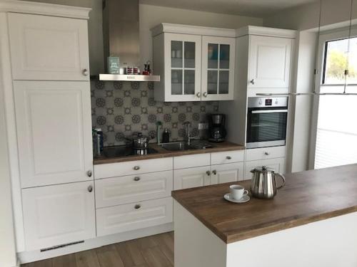 a kitchen with white cabinets and a wooden counter top at Ferienhaus Wiesenkate in Hohwacht