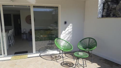 two green chairs sitting on a patio with a porch at L'appart de Fanny in Limonest