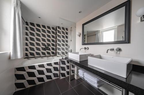 La salle de bains est pourvue de 2 lavabos et d'un miroir. dans l'établissement Hôtel Bourgogne & Montana, à Paris