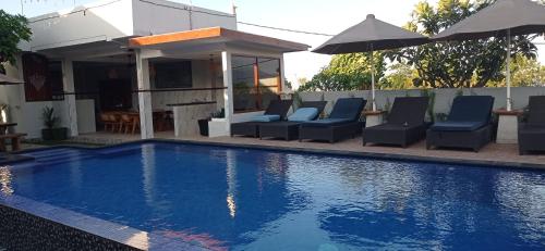 a swimming pool with chairs and an umbrella at khrisna Bungalow Tulamben in Kubu